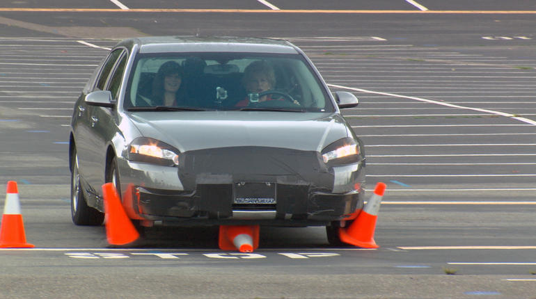 A car running over some orange traffic cones